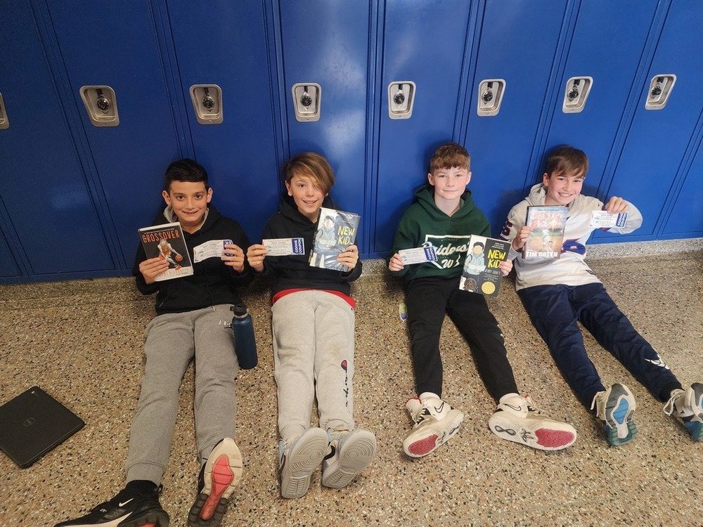 Four middle school boys reading in hall