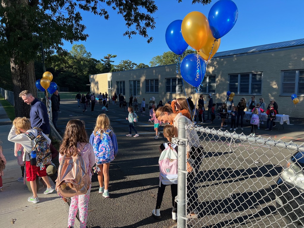 Students being greeted by teachers as they walk to school.
