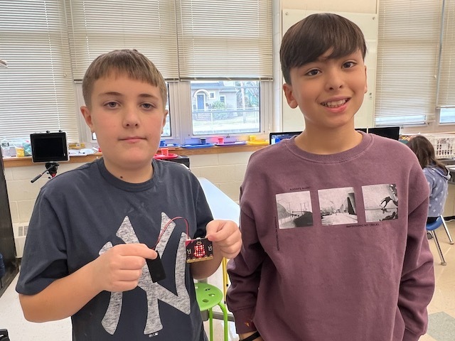 Two students showing the faces they created on the Micro:Bit